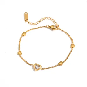 Vista detallada de una pulsera de corazón dorado con una piedra de cristal brillante.