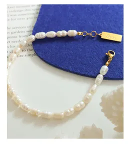 Dettaglio del bracciale di perle barocche con pendente rettangolare dorato Love