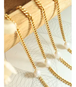 Detail of gold curb chain necklace with freshwater pearls on warm rustic background