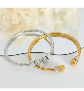 Detail of twisted cable bracelets in gold and silver with sparkling pavé zircon spheres