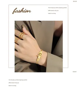 Detail of golden belt buckle bracelet and woven ring styled with a classic blazer