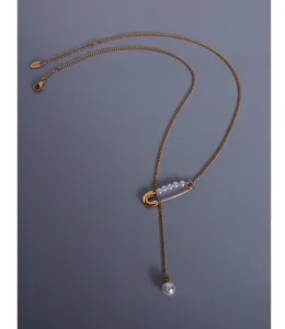 Detailed macro view of 18k gold pin necklace with pearls and fine tassel chain pendant