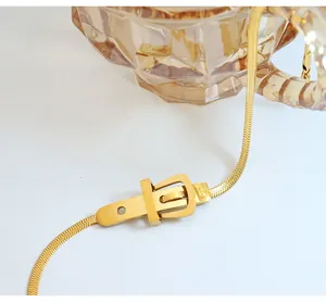 Detail of golden herringbone chain necklace with a stylish belt buckle pendant