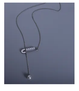 Detailed view of a silver safety pin necklace with lustrous white pearls on a fine chain