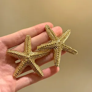 Vista dettagliata di orecchini a stella marina dorati testurizzati tenuti in mano