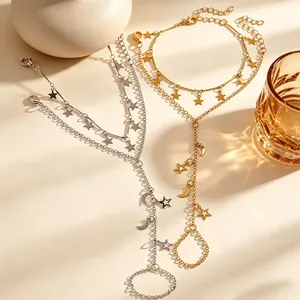 Eleganti catene da mano in oro e argento con stelle, lune e anelli sotto una luce soffusa