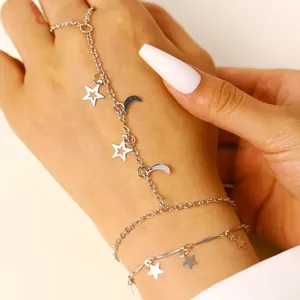 Dettaglio di un bracciale da mano a doppio strato con ciondoli a stella e luna in argento.