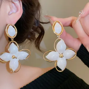Vue détaillée de boucles d'oreilles élégantes en forme de fleur blanche à monture dorée