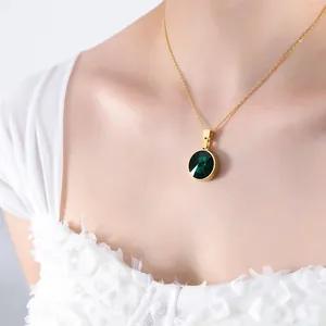 Elegant gold titanium steel necklace with a round green crystal pendant on a female model