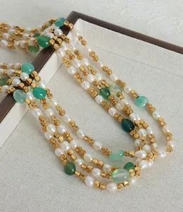 Dettaglio della collana a strati con perle naturali e pietre preziose verdi e oro