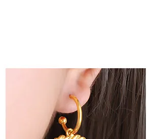 Macro di orecchini vintage in oro 18k con pendente a spirale indossati da una modella