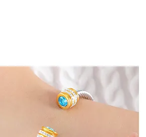 Dettaglio di un bracciale a spirale bicolore con pietra blu centrale e micro-pavé lucido