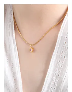 Detail view of a square pink zircon pendant on a gold box chain worn by a model