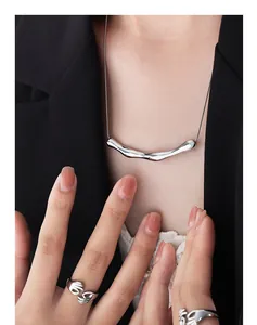 Collana lava argentata e anello mani che si abbracciano su un blazer nero elegante