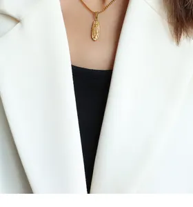 Nahaufnahme einer goldenen religiösen Medaillon-Halskette kombiniert mit weißem Blazer