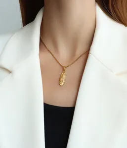 Detail der 18K vergoldeten ovalen religiösen Halskette auf weißem Blazer