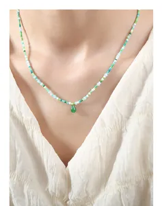 Detail of bohemian necklace with green, blue beads and translucent jade droplet pendant