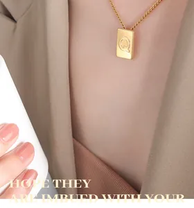 Golden square pendant necklace featuring letter Q worn on neck by a fashion model