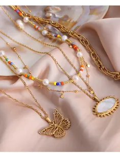 Dettaglio di collane placcate oro 18k con perle e pendente a farfalla su seta pregiata