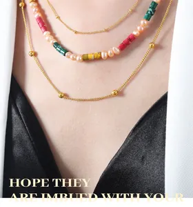 Close-up of layered necklace with natural pearls and colorful cylindrical jade stones