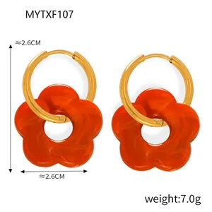 Dettaglio di orecchini a cerchio dorati da 2,6cm con fiori in resina arancione e peso