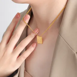 Gold square necklace with letter N pendant on minimalist chain worn by a model