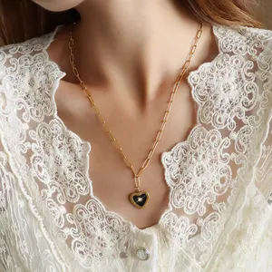 Gold paperclip chain necklace featuring a black heart pendant with a sparkling star motif