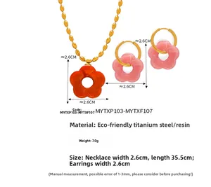 Dettaglio del set di gioielli in acciaio al titanio con pendente a fiore in resina arancione