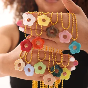 Collane con pendenti a fiore colorati e catene a sfere dorate su modella femminile