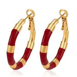 Detailed macro view of red enamel and gold bamboo-style stainless steel hoop earrings