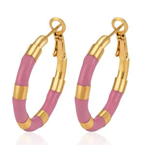 Close-up of pink enamel and gold-toned bamboo-style hoop earrings made of stainless steel