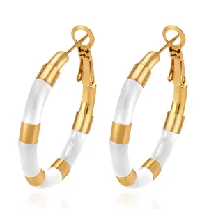 Detail of gold stainless steel bamboo hoop earrings with white enamel sections