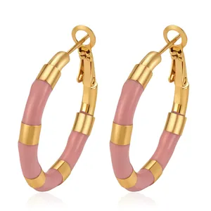 Detailed view of gold-tone stainless steel bamboo hoop earrings with pink enamel segments.
