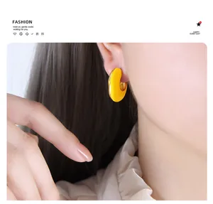Detail shot of vintage yellow enamel C-shaped earrings with polished gold accents