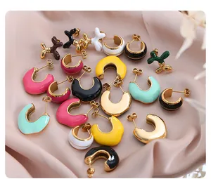 Detailed flat lay of colorful enamel earrings on pink silk featuring balloon dog studs