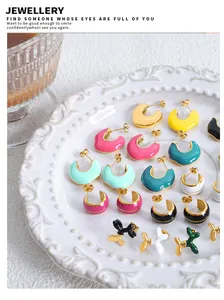 Colorful enamel C-shape hoop earrings and balloon dog studs on a white ceramic plate