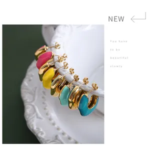 Detail of colorful macaron enamel C-shape earrings on a white vintage porcelain plate