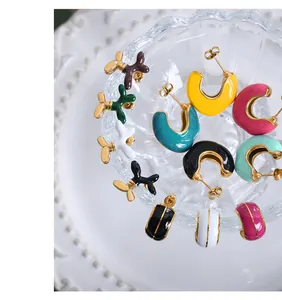 Macro shot of colorful enamel glaze earrings in balloon dog and C-hoop shapes on porcelain