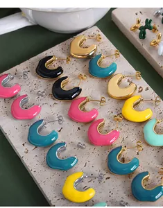 Macro shot of colorful C-shaped enamel hoop earrings on a textured stone display