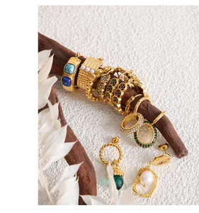 Dettaglio di orecchini e anelli vintage in oro con turchese e perla su legno