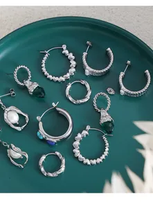 Dettaglio di orecchini vintage con cristalli verdi e perle in un vassoio di ceramica