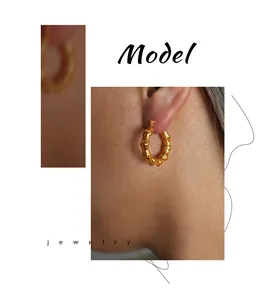 Primer plano detallado de pendientes de aro en C con textura de bambú bañados en oro