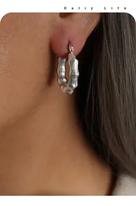 Detalle de pendiente de aro plateado con textura de bambú y elegante acabado metálico