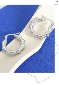 Detalle de pendientes de aro plateados con textura ondulada irregular y acabado pulido