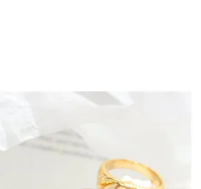 Makroaufnahme von goldenen Ohrringen im Knotendesign mit polierter Oberfläche auf Stoff