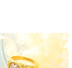 Makroaufnahme von 18k vergoldetem Ring mit Herzkristall und geprägtem Vintage-Muster