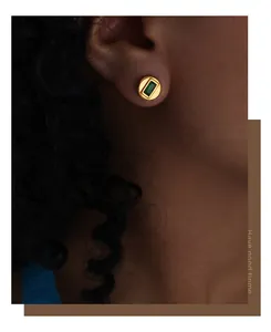 Gros plan d'une puce d'oreille dorée avec pierre verte rectangulaire sur un mannequin