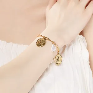 Vue détaillée d'un bracelet vintage plaqué or avec des icônes religieuses et une perle.