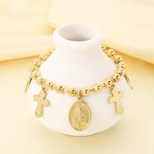 Vue détaillée du bracelet religieux en acier inoxydable doré avec breloques croix et médaille.