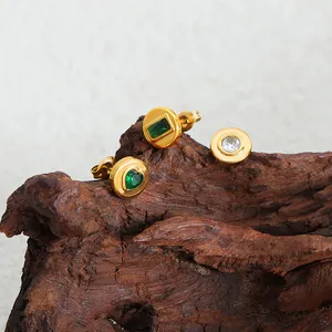 Boucles d'oreilles en acier titane doré avec zircons verts et blancs sur bois